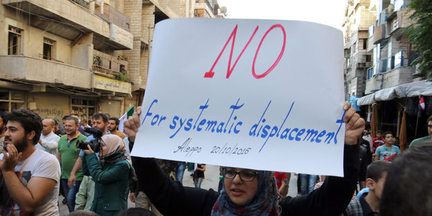 Eine Demonstrantin hält ein Schild hoch auf dem steht: Nein zu systematischer Vertreibung