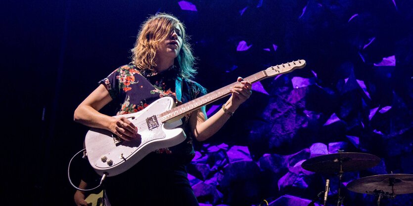 eine Frau mit einer E-Gitarre auf einer Bühne