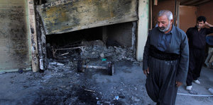 Ein Mann guckt auf den zerstörten und verbrannten Boden eines Hauses