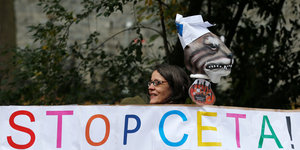Eine Frau hinter einen Protestplakat, auf dem „Stop Ceta“ steht