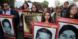 Junge Menschen protestieren mit Plakaten, auf denen die Gesichter der verschleppten Studenten zu sehen sind