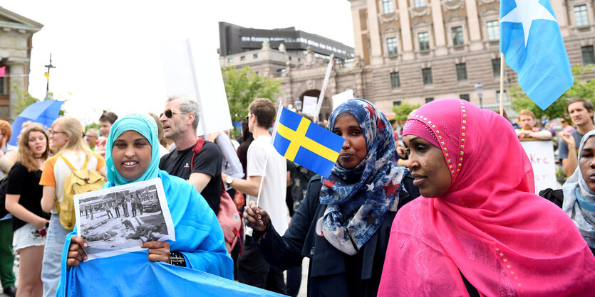 Mehrere Menschen demonstrieren mit Plakaten und Fahnen