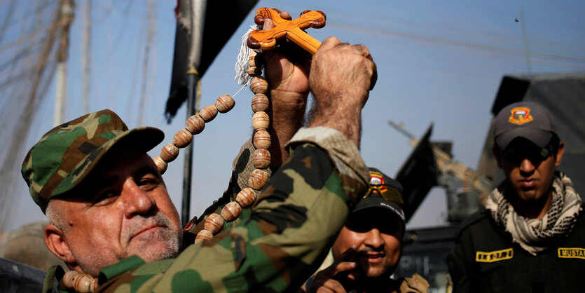 Ein Soldat hebt ein Holzkreuz hoch