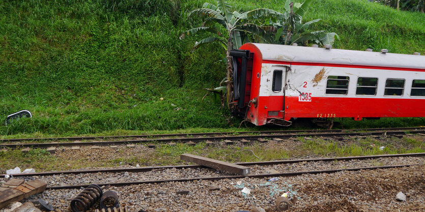 Ein rot-weißer Eisenbahnwaggon vor einer grünen Böschung