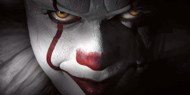 Ein Clown mit weißem Gesicht, roter Nase und rotem Mund blickt grimmig