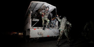 Soldaten springen bei Nacht aus einem Militärfahrzeug