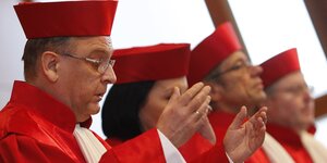 Vier Verfassungsrichter in roten Roben heben die Hände