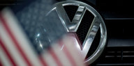 Ein Logo an einem VW-Auto zeichnet sich hinter einer USA-Fahne ab