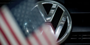 Ein Logo an einem VW-Auto zeichnet sich hinter einer USA-Fahne ab
