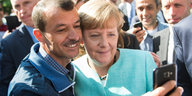 Ein Flüchtling macht ein Selfie mit Angela Merkel