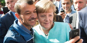 Ein Flüchtling macht ein Selfie mit Angela Merkel