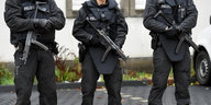 Drei bewaffnete Polizisten in schwarzen Uniformen