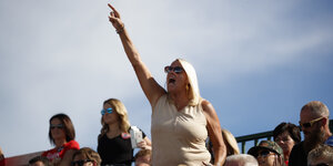 Eine Frau ragt aus einer Gruppe Trump-Anhänger heraus - und reckt den rechten Arm nach oben