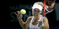 Eine junge Frau nimmt mit einem Tennisschläger Schwung, der Tennisball fliegt gerade auf sie zu