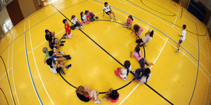 Kinder sitzen beim Schulsport im Kreis