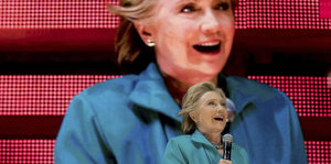 Clinton vor einer Leinwand, die ein Bild von ihr zeigt