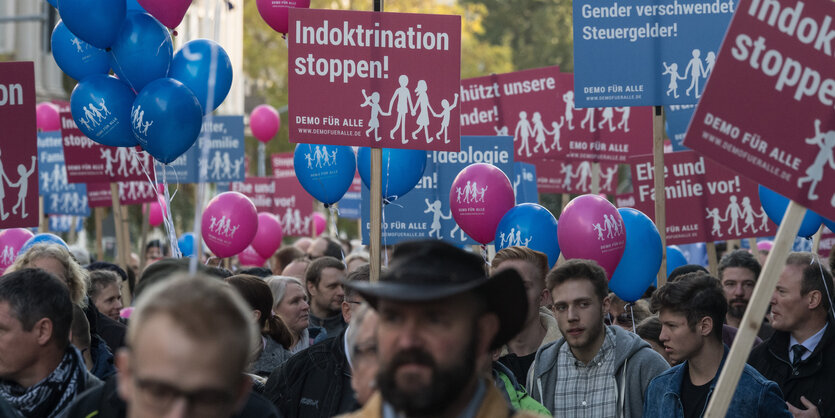 Eine Menschenmenge hält rosa und blaue Schilder und Luftballons hoch