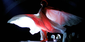 Die Tänzerin Soko als Loïe Fuller tanzt in einem lichtdurchfluteten Gewand