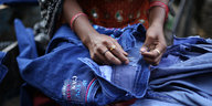 Eine Frau näht eine Jeans mit Stickerei