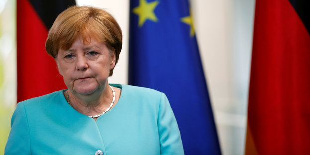 Angela Merkel läuft vor einer EU-Flagge