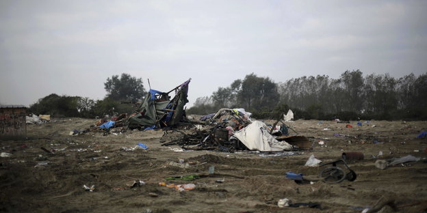 Ein Feld mit abgerissenen Zelten und Müll