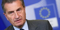 Günther Oettinger steht vor einer Europaflagge