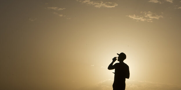Ein Mann trinkt aus einem Glas Wasser