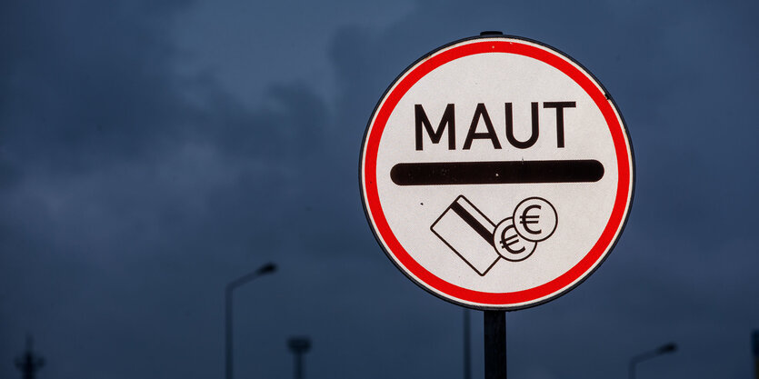 Ein Straßenschild zur Maut vor dunklem Himmel