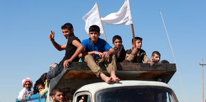 Kinder auf einem LKW halten weiße Flaggen