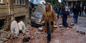 Eine Frau geht durch Trümmer