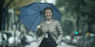 Eva Umlauf steht mit einem Regenschirm inmitten einer Allee