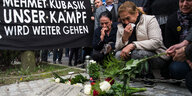 Die Witwe Elif Kubaşık und weitere Menschen knien vor einer Gedenktafel für Mehmet Kubaşık