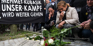 Die Witwe Elif Kubaşık und weitere Menschen knien vor einer Gedenktafel für Mehmet Kubaşık