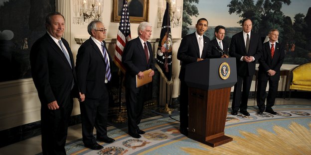 US-Präsident Obama steht vor mehreren Männern an einem Pult