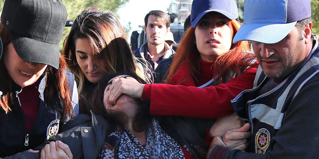 Die kurdische Politikerin Sebahat Tuncel wird von vier PolizistInnen festgehalten. Eine drückt ihren Mund zu