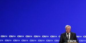 Seehofer vor blauem Hintergrund und CSU-Logos