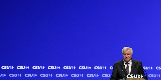 Seehofer vor blauem Hintergrund und CSU-Logos
