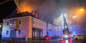 Ein Feuerwehraut vor einem brennenden Haus in Bautzen