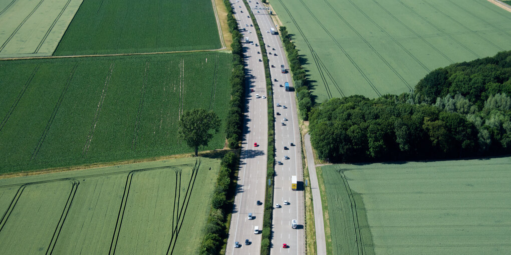 Eine Autobahn durchschneidet Felder und Wiesen.