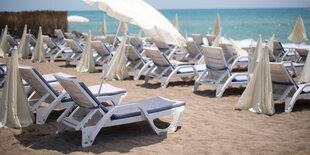 Liegestühle und Sonnenschirme am Strand