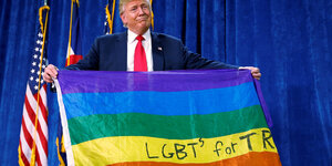 Donald Trump hält eine Regenbogenflagge mit der Aufschrift „LGBTs for Trump“