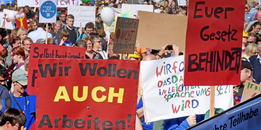 Viele Menschen protestieren, auf einem Schild steht „Wir wollen auch Arbeit"