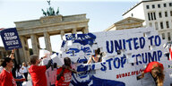 Demonstranten reißen vor dem Brandenburger Tor eine symbolische Mauer mit Trumps Konterfrei nieder