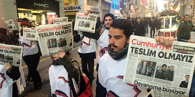 Menschen in weißen T-Shirts laufen mit Ausgaben der Zeitung "Cumhuriyet" in der Hand die Istiklal-Straße in Instanbul entlang