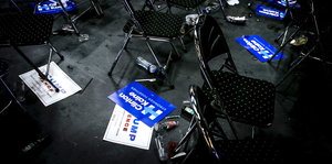 Leere Stühle stehen in einem Raum, auf dem Boden liegen Wahlkampfschilder, die für Donald Trump und Hillary Clinton werben