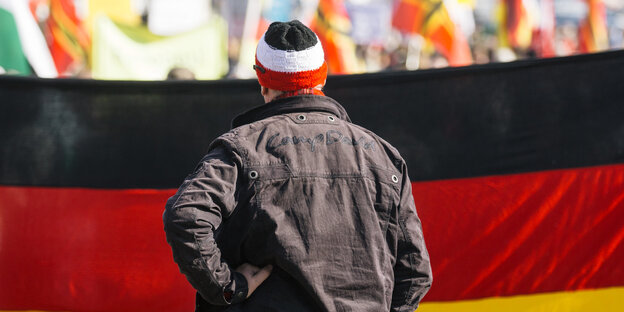 Ein Mann steht vor einer großen, aufgespannten Deutschlandfahne