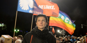 Sarah Wagenknecht steht bei einer Kundgebung vor einer Die Linke-Flagge und einer LGBTQ-Flagge
