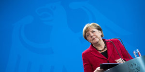 Angela Merkel hinter einem Pult, hinter ihr das Symbol des Bundesadlers
