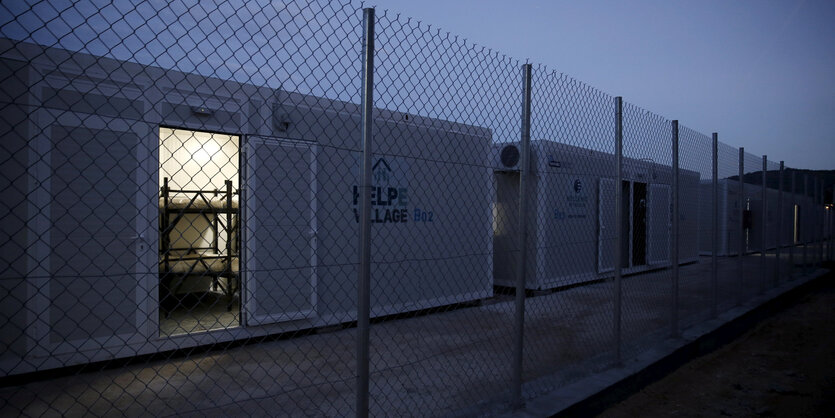 Eine Tür in einem Container ist geöffnet. Es ist dunkel und aus dem Inneren des Containers kommt Licht