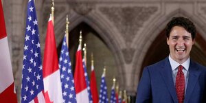 Präsident Trudeau läuft an Kanada- und USA-Flaggen vorbei